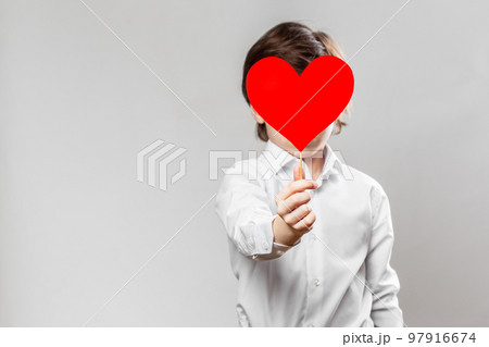 Kid Covering his Face with a Red Valentine Card Kid Covering his Face with a Red Valentine Card 97916674
