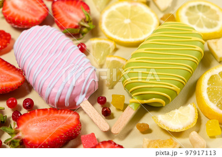 Two ice creams on a sticks - strawberry and lemon on a beige background. Summer fruit desserts. 97917113