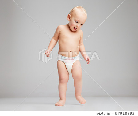 Happy cute toddler boy, baby in diaper having fun isolated over grey studio background. Concept of happy childhood, motherhood, life, birth. Happy cute toddler boy, baby in diaper having fun isolated over grey studio background. Concept of happy childhood, motherhood, life, birth. 97918593