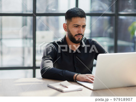 Bearded young businessman working on modern office. Consultant man thinking looking in monitor computer 97918907