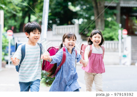 手を繋いで歩道を歩く小学生 97919392