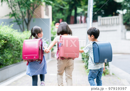 手を繋いで歩道を歩く小学生 97919397