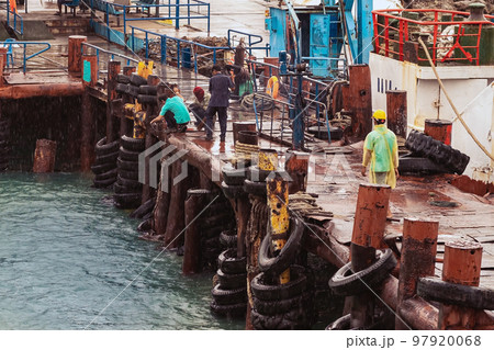 Worker welds steel parts by hand at the pier in the rain. Industrial Worker at the ferry port. Maintenance of the safety equipment on wharf bridge. Welder at the dock. Dangerous work outdoors concept. Worker welds steel parts by hand at the pier in the rain. Industrial Worker at the ferry port. Maintenance of the safety equipment on wharf bridge. Welder at the dock. Dangerous work outdoors concept. 97920068