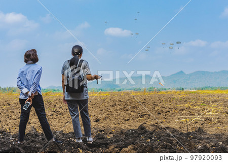 Back view of Asian mothers look with worry and concern during parachute training from airplane for army cadet with blurred image of parachute and landscape in background. Family relationship concept. Back view of Asian mothers look with worry and concern during parachute training from airplane for army cadet with blurred image of parachute and landscape in background. Family relationship concept. 97920093