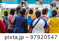 Back view of Moms watch and cheering their sons playing football in school tournament on sideline. Sport, outdoor active,  Spectator watching soccer game. Parents care and encourage their children. 97920547
