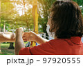 Female teacher teaches student to aim at goal. An archer teaching young man archery on field. Instructor teaching man to use bow and arrow on archery training. Archery course. Selective focus on hand. 97920555