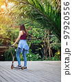 Asian woman enjoy playing and riding modern extreme stunt kick scooter without using any safety gear in home. Active sport lifestyle of young female in nature. Happy woman ride scooter without helmet. 97920556