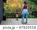 Asian woman enjoy playing and riding modern extreme stunt kick scooter without using any safety gear in home. Active sport lifestyle of young female in nature. Happy woman ride scooter without helmet. 97920558
