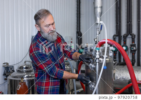 Man in plaid shirt working at the brewery and looking contented 97920758