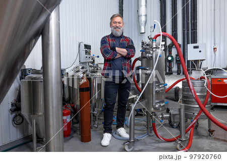 Man in plaid shirt working at the brewery and looking contented 97920760