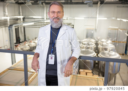 Joyous technologist posing for the camera against big metal tanks 97920845