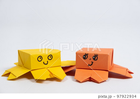 Two cute yellow and orange origami octopuses on a white background, paper animal figurines 97922934