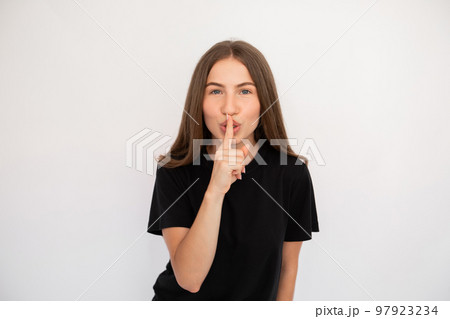 Portrait of flirty young woman making silence gesture 97923234