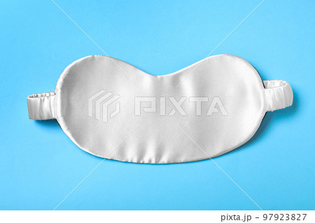 White sleeping mask on light blue background, top view. Bedtime accessory White sleeping mask on light blue background, top view. Bedtime accessory 97923827