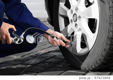 Mechanic checking tire air pressure at car service, closeup Mechanic checking tire air pressure at car service, closeup 97923868