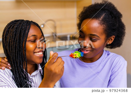 Beautiful woman feeding her wife with rainbow colorful cake and celebrating anniversary or Valentine Beautiful woman feeding her wife with rainbow colorful cake and celebrating anniversary or Valentine 97924368