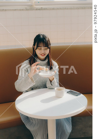 カフェでドーナツを食べる女子大生 97924540