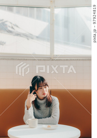 カフェで待ち合わせしている若い女子大生 カフェで待ち合わせしている若い女子大生 97924819