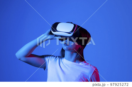 Young woman in virtual reality VR glasses playing a video games. 97925272