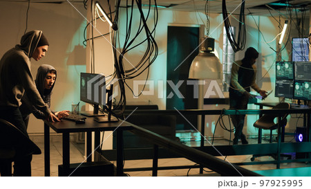 Cyber criminals working on breaking network system, using hacktivism concept to steal data. People committing cyberattack and identity theft, making privacy threats. Tripod shot. 97925995