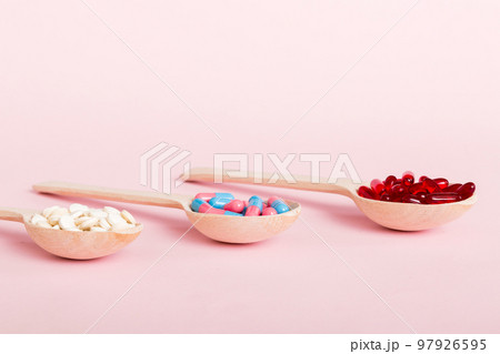 Vitamin capsules in a spoon on a colored background. Pills served as a healthy meal. Red soft gel vitamin supplement capsules on spoon Vitamin capsules in a spoon on a colored background. Pills served as a healthy meal. Red soft gel vitamin supplement capsules on spoon 97926595