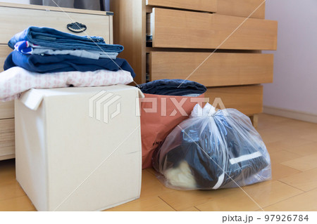 室内に置かれたポリ袋に入った衣類 積み重なった衣類 リサイクル 断捨離のイメージ 97926784