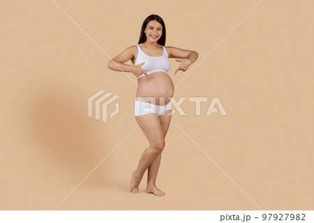 Beautiful Young Woman Expecting Baby Pointing At Her Pregnant Belly Beautiful Young Woman Expecting Baby Pointing At Her Pregnant Belly 97927982
