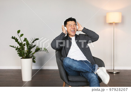 Cheerful emotional mature korean man in wireless headphones with open mouth sings song 97928207