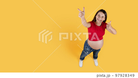 Above Shot Of Pregnant Woman Pointing At Copy Space On Yellow Background Above Shot Of Pregnant Woman Pointing At Copy Space On Yellow Background 97928349