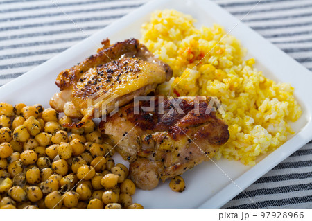 Grilled chicken thighs with garbanzo and yellow rice at plate Grilled chicken thighs with garbanzo and yellow rice at plate 97928966