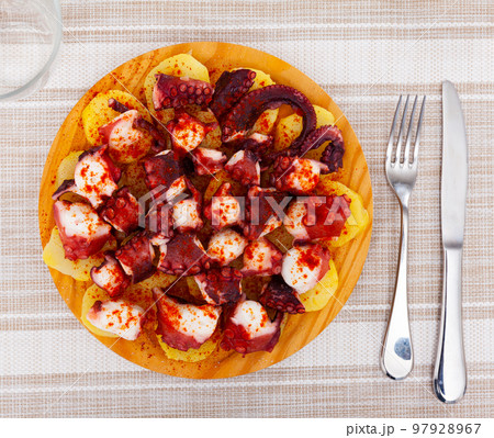 Chopped cooked octopus tentacles with smoked paprika and potato on wooden board Chopped cooked octopus tentacles with smoked paprika and potato on wooden board 97928967
