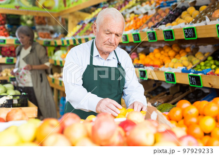 Senior man greengrocer worker setting out goods Senior man greengrocer worker setting out goods 97929233