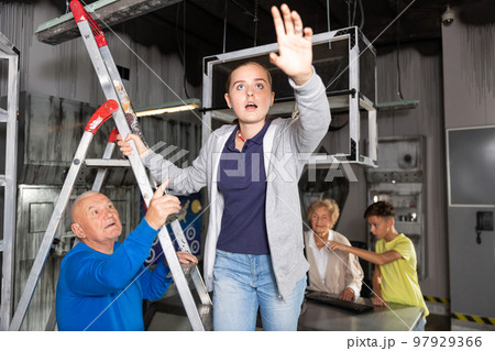 Girl on stepladder in escape room with her family 97929366