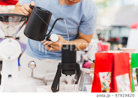Barista pour hot water into coffee aeropress in cafe. 97929820
