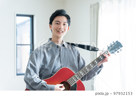 アコースティックギターを弾く若い男性 97932153