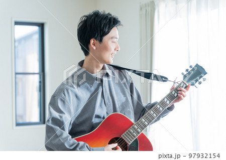 アコースティックギターを弾く若い男性 97932154
