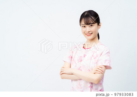 腕組みをする花柄のスクラブを着た若い女性の看護師 97933083