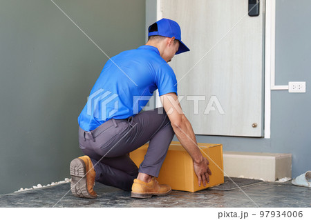 Asian courier with parcel and delivery logistic concept. Delivery man dropping the parcel in front of customer door house 97934006