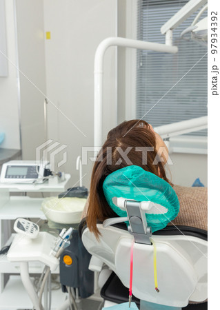 Photo of Back view of female patient visiting dentist office sitting at dental chair. Photo of Back view of female patient visiting dentist office sitting at dental chair. 97934392