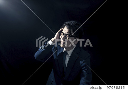 頭を抱えて苦しんでいるスーツを着たビジネスマンの男性 頭を抱えて苦しんでいるスーツを着たビジネスマンの男性 97936816