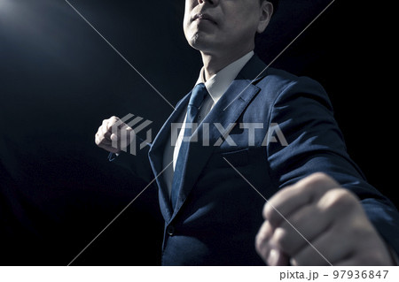 拳を上げて殴りかかってくるスーツ姿の男性 97936847