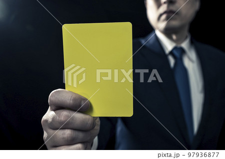 イエローカードを提示する男性ビジネスパーソン イエローカードを提示する男性ビジネスパーソン 97936877