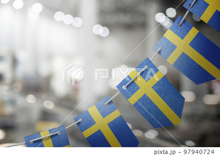 A garland of Sweden national flags on an abstract blurred background 97940724