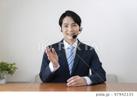 ヘッドセットをつけて話すスーツ姿の若い男性 ヘッドセットをつけて話すスーツ姿の若い男性 97942135