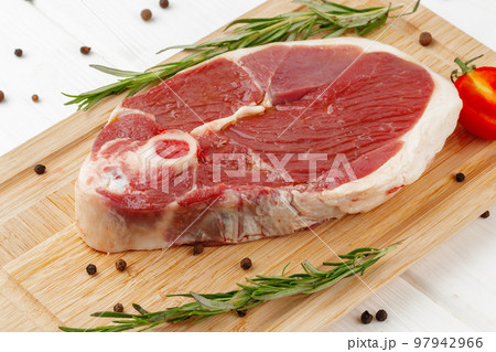 Raw lamb steak on board on white wooden table Raw lamb steak on board on white wooden table 97942966