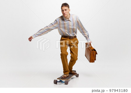 Going to work. Young man, student in retro style clothes surfing on skateboard to studying isolated over white background. 97943180