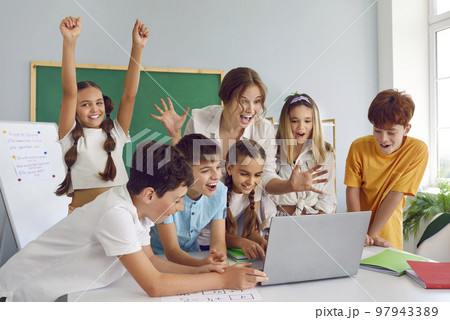 Group of happy excited school children and teacher using laptop and having fun in class 97943389
