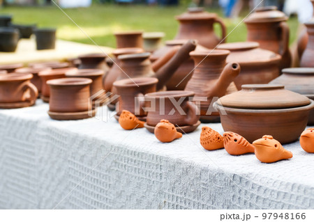 Defocus pottery from earthenware jugs mugs in nature. Set of old ceramic pot and mug, kitchen retro equipment of cooking on festival background. Ukrainian culture. Out of focus 97948166