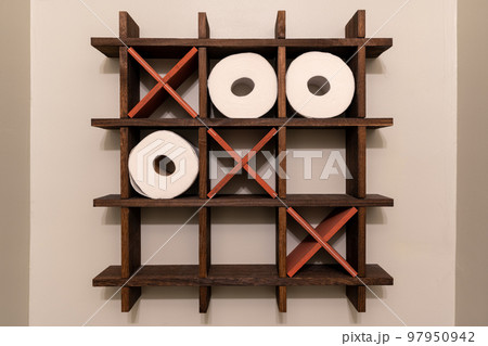 A Tic-Tac-Toe wooden shelf for rolls of toilet paper. Toilet decoration. Noughts and crosses, Xs and Os.  97950942