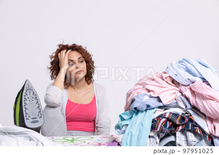 The woman can't believe she has so many men's shirts to iron this time. The woman can't believe she has so many men's shirts to iron this time. 97951025